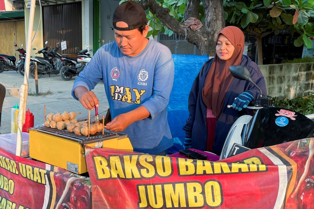 Rahmat Hidayat now earns less than half of what he used to make selling grilled meatballs. - Reuters image